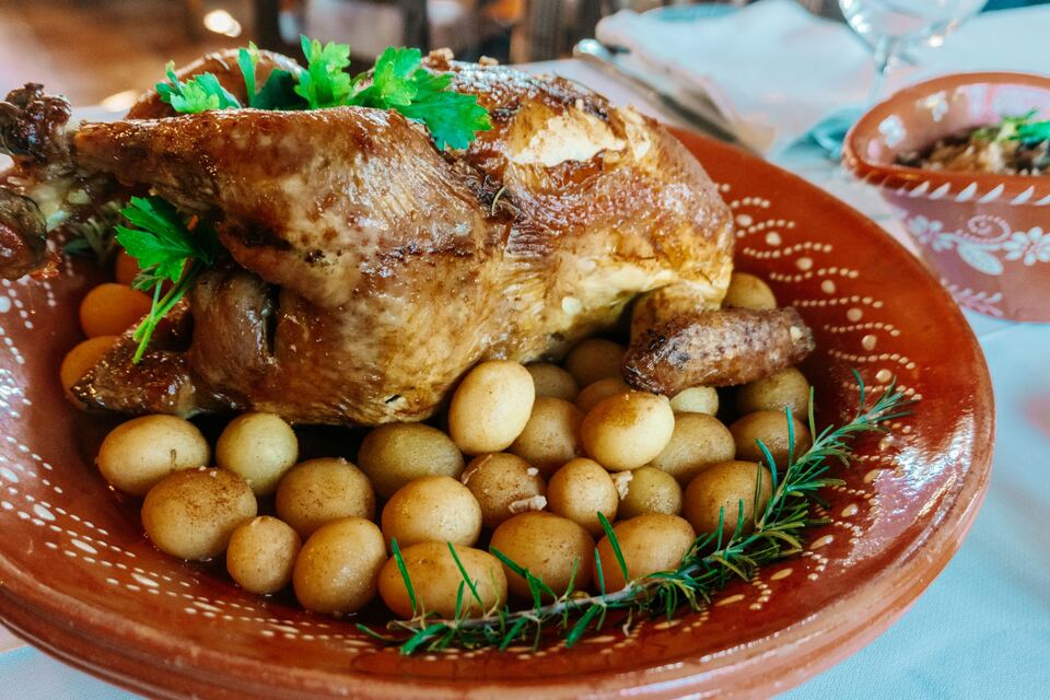 Frango assado com batatinhas numa travessa de barro