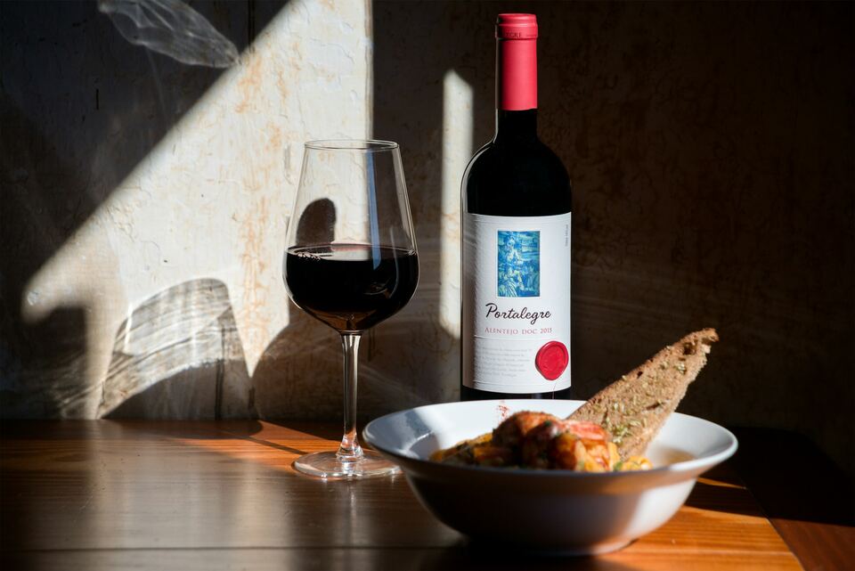 Garrafa de vinho tinto, copo cheio e taça com pão ao fim da tarde